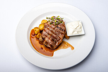Sous-vide neck of pork with roasted potatoes, bacon and onions with garlic dip