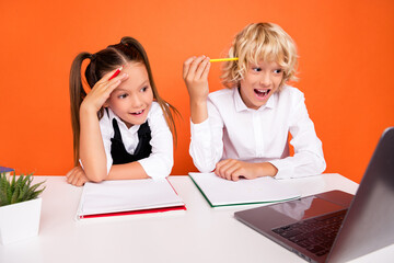 Photo of excited schoolkids remote lesson look laptop screen wear uniform isolated orange color background