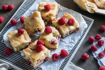 Blondie, white chocolate brownie with raspberry on a grey wooden background, selective focus