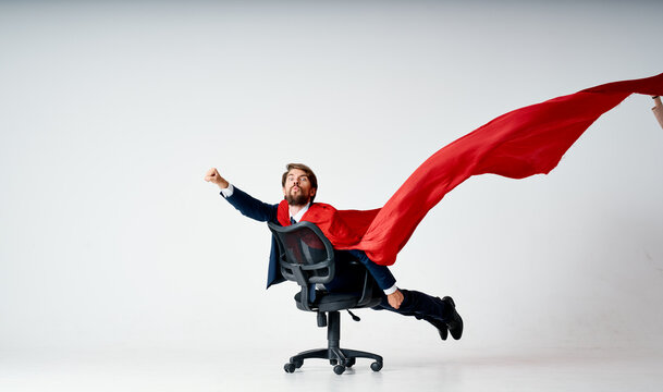 bearded man in a suit rides in a chair red superman cape