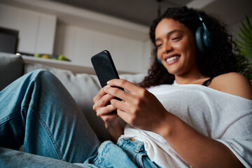 Mixed race female teen texting on cellular device relaxing at home