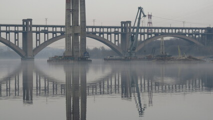 Lustrzane odbicie budowy mostu przez rzekę Dniepr w Zaporożu, Ukraina