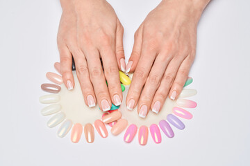 woman with well-groomed hands and healthy nails holding palette with swatches collection of nail Polish for manicure
