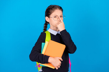 Obraz premium Photo of serious strict cool confident schoolgirl adjust spectacles hold books wear rucksack isolated on blue color background