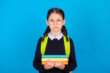 Photo of stressed depressed negative mood schoolgirl prepare exam hold pile books isolated on blue color background