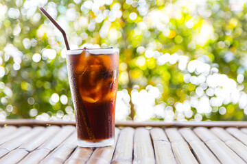 Beverage glass with ice cubes on bamboo table