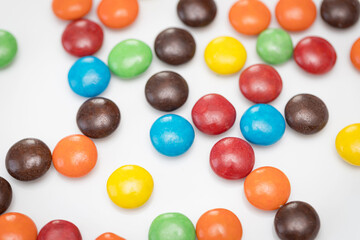Variety of colorful candies coated on white background