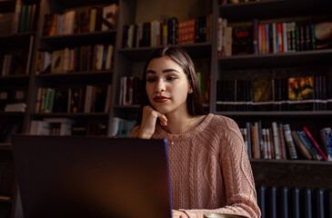 Portrait of young woman working on using laptop at coffee shop.