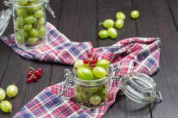 Two glass jars with green gooseberries on check napkin