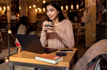 Portrait of young woman working on using laptop at coffee shop.