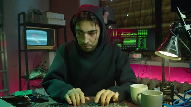 Careful hacker stealing information with usb from laptop, preparing to break password and looking around. Young man criminal entering room and typing on keyboard. Professional hacker attack. 