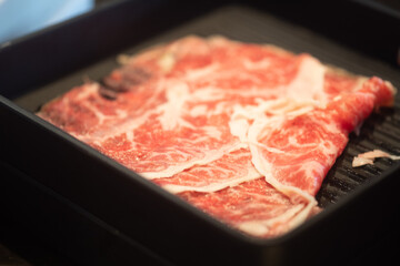 Sliced raw wagyu beef in a black tray