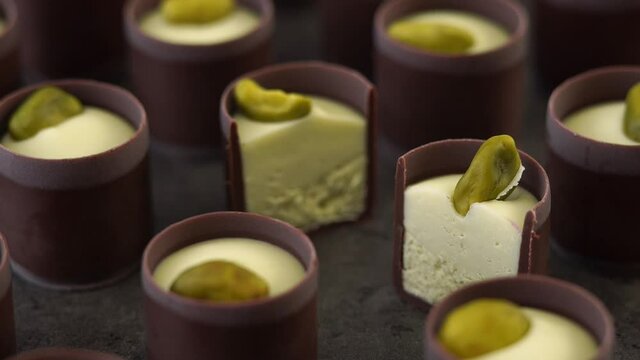 Camera movement of chocolate candies with creamy filling cream and pistachio nuts. Close up of food dessert background.