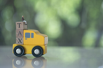 Miniature businessman sit on three wooden cubes with word tax on yellow car.