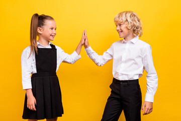 Profile photo of two schoolkids give high five done exam wear school uniform isolated yellow color...