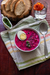 Cold borsch, summer beet soup with fresh cucumber boiled egg in a white bowl, bread, lemon. Traditional European food, delicious lunch