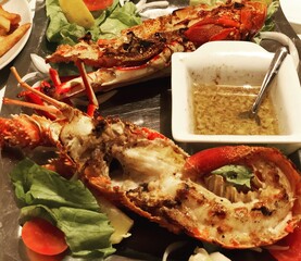 A plate with seafood and lobster. A beautiful serve, a gravy boat with sauce.