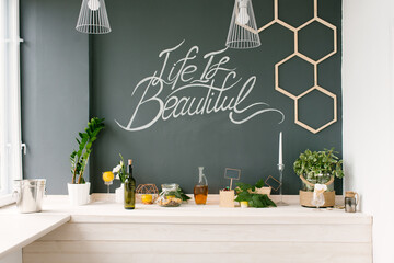 A graphite wall and a light wooden kitchen. Decor and kitchen utensils on the table
