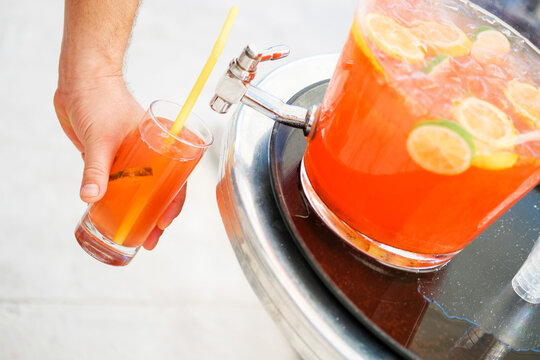 Man Hand Pouring Fresh Sorbet Fruit Juice Or Alcohol Punch From Drinking Tank Machine At Party.