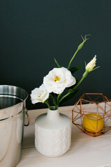 A white ceramic vase and an artificial white eustoma flower in it. Decor in the dining room or kitchen
