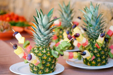 Delicious handmade fruit appetizer catering food on a table and construction of various fruits on ananas .