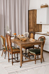 Kitchen table with food and kitchenware with a variety of wooden chairs in the Scandinavian style