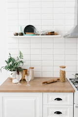 Fototapeta na wymiar Bright kitchen in the Scandinavian style. Pasta in a glass jar, houseplant, glasses and kitchen utensils. Decor