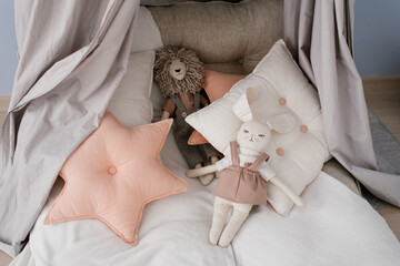 Various pillows: square and sprocket, soft toys on the children's bed
