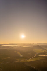 Obraz premium aerial view of sunrise in the countryside with light mist over the mountains and clear skies.