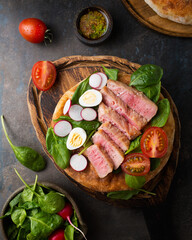 Salad with tuna, cherry tomatoes, spinach and radish Dressing of spicy sauce with mustard. Food styling of fish salad. Organic food. French nicoise salad with quail eggs. Serving salad on a bun.