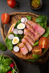 Salad with tuna, cherry tomatoes, spinach and radish Dressing of spicy sauce with mustard. Food styling of fish salad. Organic food. French nicoise salad with quail eggs. Serving salad on a bun.