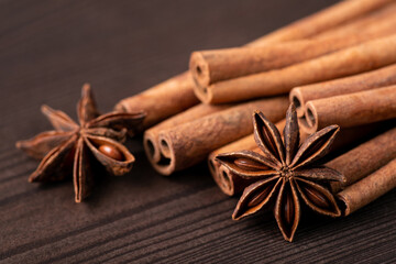 Obraz na płótnie Canvas Cinnamon sticks and anise stars on wooden table. Bright photo of spices for bakery on dark background
