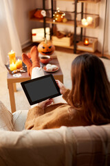 halloween, holidays and leisure concept - young woman with tablet pc computer at home