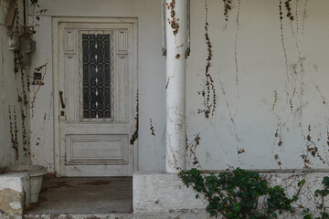 old house porch with vintage door and withered plants