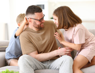 Positive happy family of three enjoying carefree time together at home, dad playing with kids