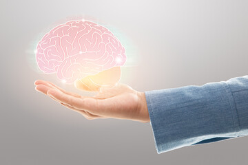 Female doctor holding brain illustration against the gray background. Mental health protection and...