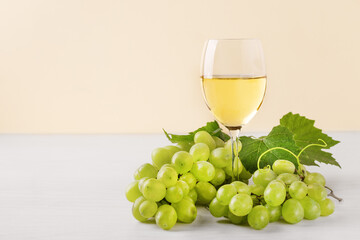 Glass of white wine and white grape on wooden table. Wine composition with copy space for design. Still life of wine and grape.