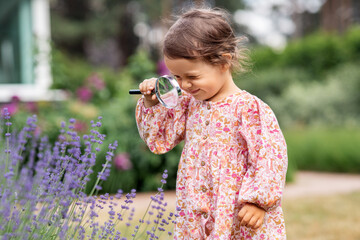 childhood, leisure and people concept - happy little baby girl with magnifier looking at lavender...