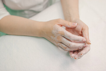 Female hands in white cream, on a white background.