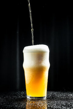 pouring beer into glass, beer, splash, black background. vertical image. place for text