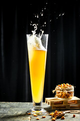 beer being poured into glass with gourmet snacks for beer, splash, black background. vertical...
