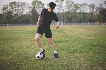 Sports and recreation concept a male soccer player wearing black t-shirt and pants practicing...