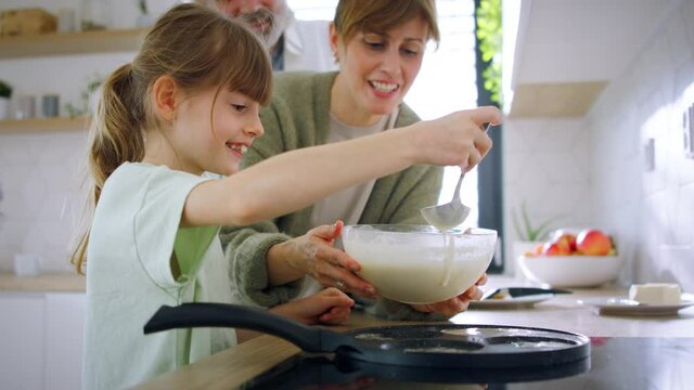 Beautiful family at home making a pancakes together.