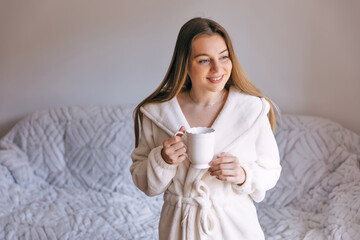 Woman in bathrobe start day with cup of coffee in morning