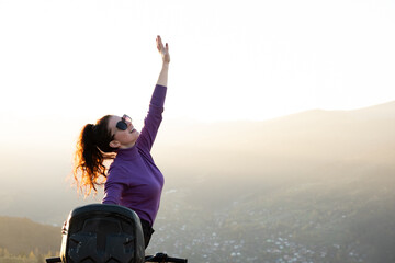 Happy woman driver enjoying extreme riding on ATV quad motorbike in summer mountains at sunset.