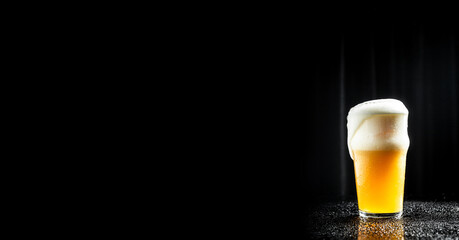 Cold glass filled with beer. splash, black background. Long banner format