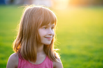 Portrait of young pretty child girl relaxing outdoors on warm summer day.