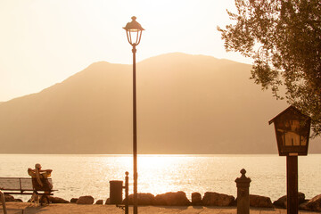 Fototapeta na wymiar Rida del GADRA, ITALY-July 20, 2021: a girl on the Lake Garda admires the sunset