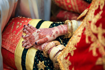 Close up hands and nails of Asian Muslim bride with henna paint tattoo and jewelry in a wedding ceremony. Traditional Minangkabau culture heritage from West Sumatra, Indonesia. 