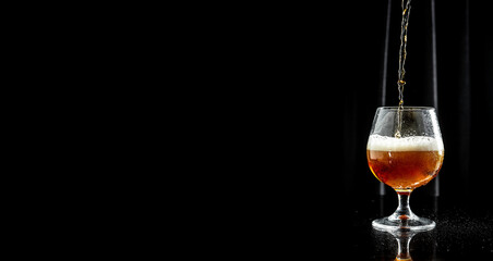 pour beer into a Cold glass filled. splash, black background. Long banner format